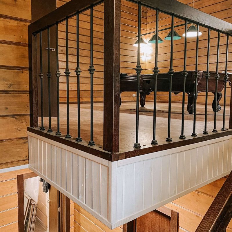 Г-образная деревянная лестница из ясеня с ковкой в брусовом доме