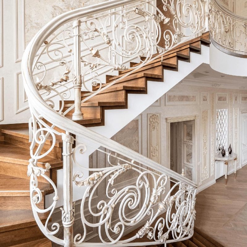 Отделка парадной лестницы из бетона дубом с художественной ковкой
